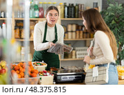 Woman store employee offers customer to choose sweets, shows packed various dessert options. Стоковое фото, фотограф Яков Филимонов / Фотобанк Лори