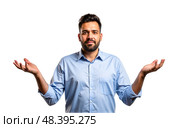 Man in blue shirt shrugs, hands raised, confused expression, isolated white background, questioning gesture, casual look, uncertainty. Стоковое AI-изображение, AI-художник Павел Муравьев / Фотобанк Лори
