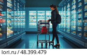 A woman with shopping cart examining frozen food section, cool blue lighting from freezers creating dramatic contrast. Стоковое AI-видео, аниматор Sergey Grishin / Фотобанк Лори