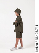 Stylish Child Poses Confidently in Trendy Olive Green Outfit Against a Minimalist Studio Backdrop. Стоковое фото, фотограф Aleksandr Golubev / Фотобанк Лори