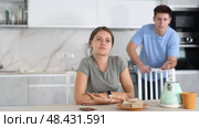 Upset young woman sitting at the kitchen-table with her back to her husband disputing with her. Стоковое видео, видеограф Яков Филимонов / Фотобанк Лори