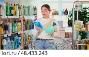 Girl housewife in household store examines package, chooses household chemical spray. Стоковое видео, видеограф Яков Филимонов / Фотобанк Лори
