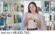 Young female customer choosing cosmetics, looking for lipstick and choosing from several samples in cosmetics shop. Стоковое видео, видеограф Яков Филимонов / Фотобанк Лори