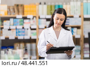 Middle-aged female pharmacist restocking with tablet in drugstore. Стоковое фото, фотограф Яков Филимонов / Фотобанк Лори