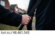 Urban danger scene with hand forcefully grabbing backpack strap in tense daylight encounter. Стоковое AI-изображение, AI-художник Ольга Березина / Фотобанк Лори