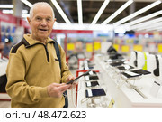 Senor man pensioner buying modern tablet digital in showroom of digital electronic goods store. Стоковое фото, фотограф Татьяна Яцевич / Фотобанк Лори