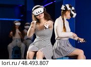 Girls wearing virtual reality glasses play in pairs, against each other, manipulating objects or shooting at targets using joysticks in their hands. Стоковое фото, фотограф Яков Филимонов / Фотобанк Лори