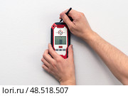 Man using stud finder to locate framing studs located behind the walling surface. Using a wall scanner to identify hidden electrical wiring. Space for text. Стоковое фото, фотограф Луиза Налимова / Фотобанк Лори