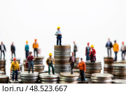 Miniature workers and businesspeople standing on stacks of coins symbolizing income inequality, labor market, salary differences, financial hierarchy, and economic disparity. Copy space. Banner. Стоковое AI-изображение, AI-художник Евгений Демидюк / Фотобанк Лори