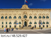 VALLETTA, MALTA - NOVEMBER 12, 2018 - Exterior view of the Auberge de Castille in Castille Square with people walking by. Редакционное фото, фотограф Сергей Богомяко / Фотобанк Лори