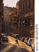 VALLETTA, MALTA - NOVEMBER 12, 2018 - Hilly ancient streets view with colourful balconies, people and cars in the medieval city. Редакционное фото, фотограф Сергей Богомяко / Фотобанк Лори