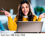 A woman is sitting at a desk with a laptop open and a pen in her hand. Стоковое AI-изображение, AI-художник Ярославский Максим / Фотобанк Лори