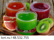 Three glasses of juice with a kiwi on the right. Стоковое AI-изображение, AI-художник Ярославский Максим / Фотобанк Лори