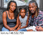 A family of three, a man, a woman and a child, are sitting on a couch. Стоковое AI-изображение, AI-художник Ярославский Максим / Фотобанк Лори