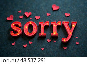 Colorful illuminated letters spelling sorry surrounded by small red hearts on a dark textured background, conveying a heartfelt apology and emotional expression of love. Стоковое AI-изображение, AI-художник Котова / Фотобанк Лори