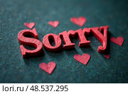 Red letters spelling "Sorry" on a textured green background, surrounded by small pink hearts, conveying a heartfelt apology and emotional sentiment in a creative design. Стоковое AI-изображение, AI-художник Котова / Фотобанк Лори