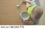 top view baby eating himself holding teaspoon from silicone plate sitting table. Стоковое видео, видеограф Olesia Kondrateva / Фотобанк Лори