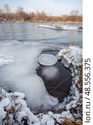 Unfrozen river in winter. Chunks of ice float in the water near the shore. Nearby islets with yellow, dry grass. Стоковое фото, фотограф Андреева Тамара Викторовна / Фотобанк Лори