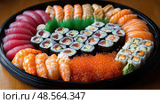 An elaborate selection of sushi and sashimi awaits diners, showcasing vibrant colors and fresh seafood, perfect for any special occasion. Стоковое AI-изображение, AI-художник Данила Большаков / Фотобанк Лори