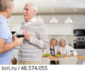 Elderly men have withdrawn from their female companions, stand with glass of wine in hands, chatting. Стоковое фото, фотограф Яков Филимонов / Фотобанк Лори