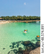 Tropical beach scene in Vietnam with swimmers in life jackets, crystal clear water, horizon view, white sand, rocks and palm trees. Nha Trang coastline. Стоковое фото, фотограф Татьяна Терехина / Фотобанк Лори