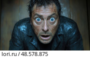A man sits in a dimly lit room with wet hair, wide blue eyes filled with shock, showing an intense emotional reaction after a mysterious incident. Стоковое AI-изображение, AI-художник Данила Большаков / Фотобанк Лори