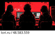 Three people wearing headphones work intently at their computers, surrounded by a backdrop of glowing red, engaged in programming tasks. Стоковое AI-изображение, AI-художник Данила Большаков / Фотобанк Лори