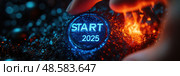 A hand activates a glowing start 2025 button, illuminating a textured background with vibrant light in a modern, tech-inspired environment. Стоковое AI-изображение, AI-художник Данила Большаков / Фотобанк Лори