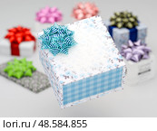 Gift box with a blue bow in focus, surrounded by colorful presents. Festive mood and decorative wrapping elements. 3D render. Стоковая иллюстрация, иллюстратор Татьяна Грачева / Фотобанк Лори