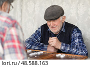 Пенсионеры с азартом играют в нарды. Активное долголетие. Редакционное фото, фотограф Evgenia Shevardina / Фотобанк Лори