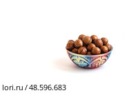 Clay bowl with macadamia nuts in shell on white background, copy space. Стоковое фото, фотограф Зарифа Арсланова / Фотобанк Лори