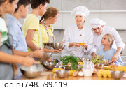 During cooking lesson, female cook tells children about culinary rules, guy assistant helps child. Стоковое фото, фотограф Яков Филимонов / Фотобанк Лори