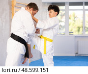 Underage boy and middle-aged man performing karate techniques in pair. Стоковое фото, фотограф Яков Филимонов / Фотобанк Лори