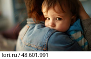 A young child is tightly gripping a womans shoulder, showing a strong bond and dependency between the two individuals. Стоковое AI-изображение, AI-художник Данила Большаков / Фотобанк Лори