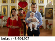 Belarus, Gomel, April 29, 2018. Church of Volotovo. Baptism of the Child.The Godfather and godmother on the rite of the right child's baptism. Редакционное фото, фотограф Лазаренко Светлана / Фотобанк Лори