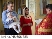 Belarus, Gomel, April 29, 2018. Church of Volotovo. Baptism of the Child.A child at the rite of baptism. Godparents hold the baby in the hands of the rite of baptism. Редакционное фото, фотограф Лазаренко Светлана / Фотобанк Лори