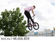 Belarus, Gomel, June 24, 2018. Central park. Extreme cycling.Jumping on a bicycle against the backdrop of a city of green wood. Редакционное фото, фотограф Лазаренко Светлана / Фотобанк Лори