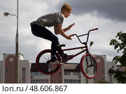 Belarus, Gomel, June 24, 2018. Central park. Extreme cycling.A dangerous trick on a bicycle against the backdrop of the city.Teenager on a bicycle. Редакционное фото, фотограф Лазаренко Светлана / Фотобанк Лори
