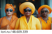 Three women wearing coordinated orange outfits and hats pose together, showcasing their style and camaraderie during a sunny outdoor gathering. Стоковое AI-изображение, AI-художник Данила Большаков / Фотобанк Лори