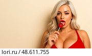 Attractive blonde woman licking red candy wearing red dress sensual provocative beauty glamour fashion portrait temptation desire sweet concept. Стоковое AI-изображение, AI-художник Павел Муравьев / Фотобанк Лори