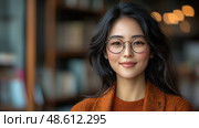 A warm-hearted woman in glasses smiles, surrounded by books in a cozy library filled with soft, inviting lighting. Стоковое AI-изображение, AI-художник Данила Большаков / Фотобанк Лори