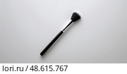 Makeup brush rests on a clean surface, highlighting its soft bristles and sleek design for beauty enthusiasts and professionals alike. Стоковое AI-изображение, AI-художник Сергей Толмачёв / Фотобанк Лори