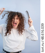 Curly hair tangles badly causing painful discomfort while brushing and combing hair at home or salon. Стоковое фото, фотограф Svetlana Golovco / Фотобанк Лори