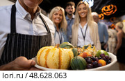 A man is holding a plate of food, including a pumpkin and a variety of fruits. Стоковое AI-изображение, AI-художник Ярославский Максим / Фотобанк Лори
