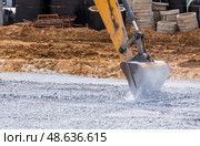 An excavator on a construction site in close-up. The excavator rams the crushed stone with a bucket for construction. Heavy machinery for construction and landscaping. Стоковое фото, фотограф Photojuli / Фотобанк Лори