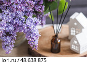 The aroma diffuser. Lilac-scented spring perfumes for the home in a glass bottle with chopsticks as an air freshener in the house. Aromatherapy, cozy atmosphere, comfort and relaxation. Стоковое фото, фотограф Photojuli / Фотобанк Лори