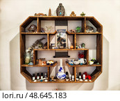 Phu Quoc, Vietnam - April 04, 2025: Decorative wooden shelf displaying collectibles and small artifacts in a cozy living space. Редакционное фото, фотограф Кривошеина Елена Леонидовна / Фотобанк Лори