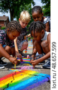 A group of children are painting a rainbow on the ground. Стоковое AI-изображение, AI-художник Ярославский Максим / Фотобанк Лори
