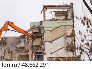 Heavy machinery is tearing down a dilapidated building under overcast skies, marking an end to its structure and beginning of redevelopment. Стоковое фото, фотограф Данила Большаков / Фотобанк Лори