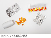 Pillbox by days of the week with fish oil and various pills, capsules and jars scattered on a white background, top view. Стоковое фото, фотограф Кашапова Эльвира / Фотобанк Лори